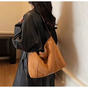 Detail of caramel suede hobo bag with exquisite stitching and refined logo plaque