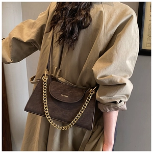 Detail view of vintage dark brown crossbody bag with gold chain strap on a khaki trench coat