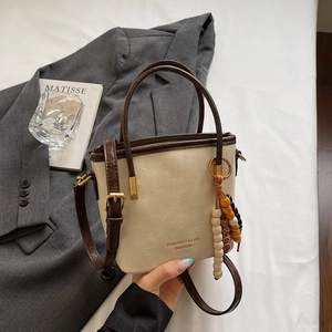 Dettaglio della borsa a secchiello beige con manici marroni e charm di perle colorate
