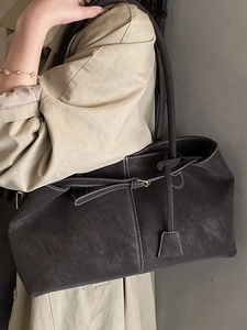 Chic dark grey suede tote bag with contrast stitching and shoulder strap on model