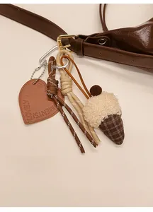Détail du pendentif cœur en cuir et de la noix en peluche sur un sac vintage marron