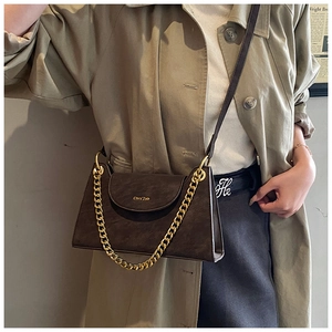 Detail of dark brown leather crossbody bag with chunky gold chain and thin shoulder strap