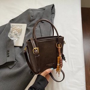 Vista dettagliata della borsa a secchiello marrone con logo dorato e nappa di perle