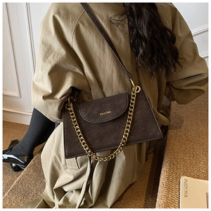 Detailed view of deep brown faux suede crossbody bag with decorative gold chain and leather strap