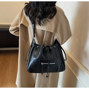 Rear view of a black quilted leather bucket bag worn with a classic beige trench coat