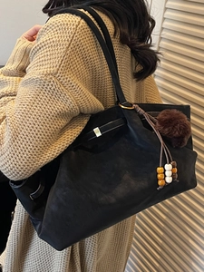 Chic black faux suede tote bag with metal buckle and plush charm for winter fashion