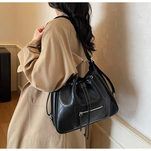 Detail view of black quilted leather bucket bag with silver zipper and drawstring