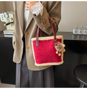 Détail du sac seau en daim rouge avec bordure en molleton beige et pendentif ourson