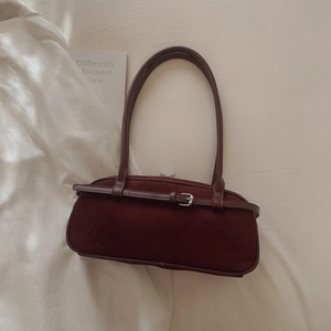 Macro view of burgundy faux suede Boston bag with matte texture and buckle detail