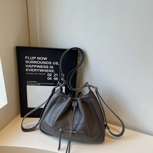Detailed close-up of dark grey quilted leather bucket bag with zipper pocket and drawstring