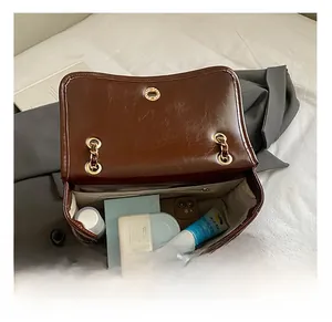 Internal view of dark brown flap bag showing compartments for phone and cosmetics