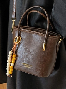 Borsa a secchiello retrò in pelle marrone con texture vintage e ciondolo di perle