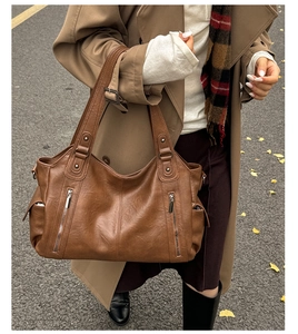 Détail d'un grand sac fourre-tout marron avec fermeture éclair et rivets métalliques