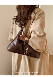 Détails d'un sac cabas rétro marron foncé avec pompons et breloques décoratives