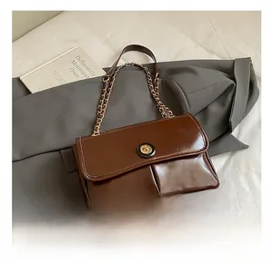 Detail view of coffee oil-wax leather shoulder bag with gold chain and metal clasp