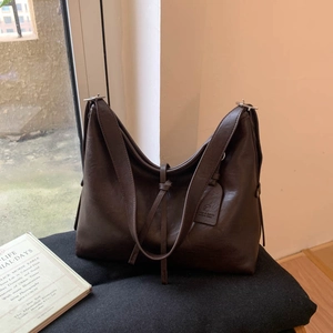 Détail d'un sac cabas en cuir marron foncé avec étiquette et bandoulière