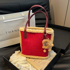 Détail du sac cabas en daim rouge avec bordure en peau lainée et breloque lion en boîte
