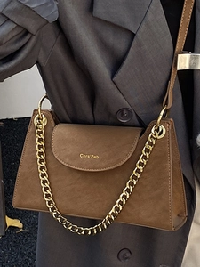 Brown vintage leather crossbody bag with gold chain strap worn over a grey blazer jacket
