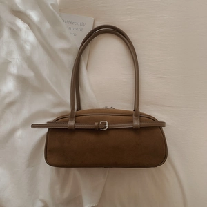 Detailed close-up of dark brown suede Boston bag with vintage metal buckle and slim straps