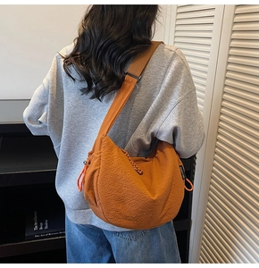 Dettaglio della borsa hobo arancione plissettata con tessuto testurizzato e tracolla