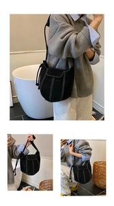 Detail of black suede bucket bag showing contrast white stitching and minimalist aesthetic
