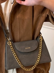 Modern dark grey trapezoid crossbody bag with matte finish and gold chain strap
