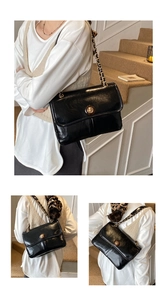 Detail of black oil-wax leather flap bag with gold chain and amber clasp on model