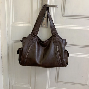 Vue détaillée d'un grand sac cabas marron en similicuir avec des fermetures éclair en métal