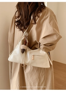 Détail du sac fourre-tout en cuir crème avec poche zippée élégante et anneau en métal argenté