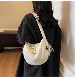 Dettaglio della borsa a tracolla bianco crema con trama goffrata e marchio su modello