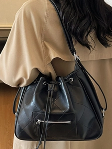 Classic black quilted bucket bag in soft leather shown on a model with a khaki coat