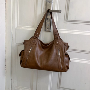 Vue détaillée d'un sac cabas marron avec fermetures éclair argentées et poches latérales