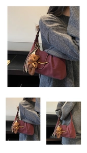 Detail of burgundy underarm bag with gold metal buckle and cute teddy bear charm