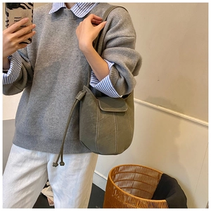 Close-up of olive green suede bucket bag with decorative stitching and drawstring detail
