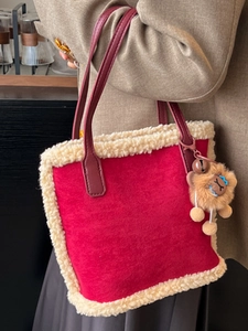 Sac fourre-tout en daim rouge avec bordure en peluche et pendentif ours sur un modèle