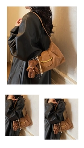 Detail of brown underarm bag featuring gold metal accent and cute plush bear charm decoration