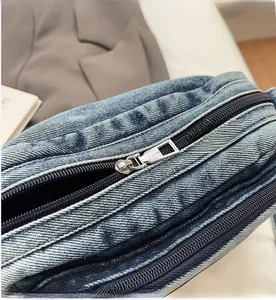 Gros plan des fermetures éclair en métal argenté sur un sac à bandoulière en denim