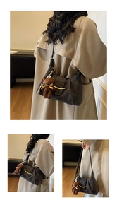 Detail of vintage pleated leather underarm bag with golden crescent buckle and bear charm