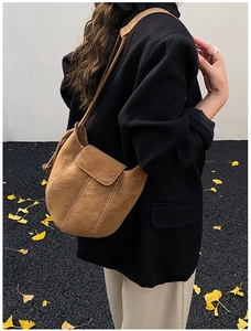 Detail view of brown suede bucket bag with white contrast stitching and adjustable strap