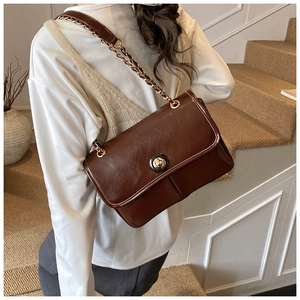 Detail of vintage brown textured leather crossbody bag with gold chain and round clasp