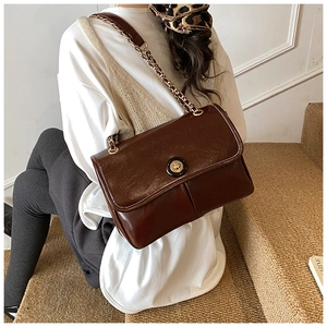 Brown vintage faux leather crossbody bag with gold chain strap shown on model