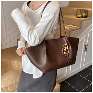 Detailed view of dark brown oil wax leather tote bag with vintage beaded charm