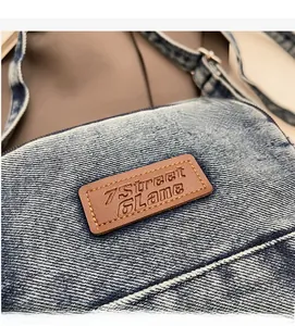 Détail du sac en denim bleu avec un patch en cuir marron et boucle en métal argent