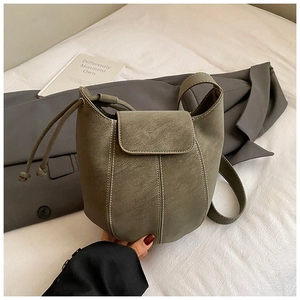 Detailed close-up of retro matte suede bucket bag with contrast stitching and leather strap