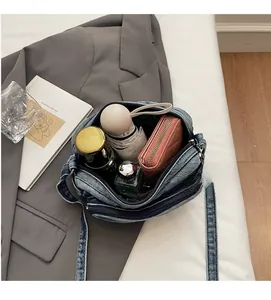 Vue détaillée du sac bandoulière en jean montrant l'intérieur spacieux avec portefeuille