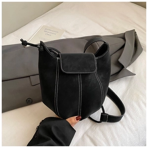 Detailed view of black matte leather bucket bag featuring white contrast stitching detail