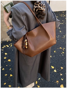 Macro shot of dark brown leather tote bag with stylish beaded tassel on street background