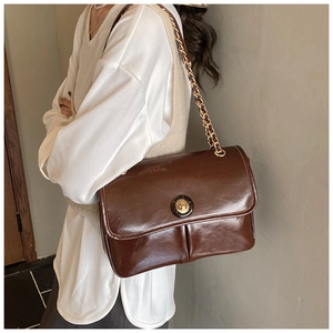 Detail of vintage brown glossy leather shoulder bag with gold clasp and chain strap