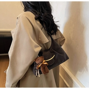 Detail of dark brown matte underarm bag with crescent buckle and bear pendant charm
