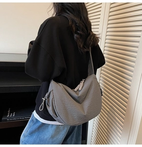 Dettaglio borsa hobo grigia testurizzata con tirante intrecciato ed etichetta nera